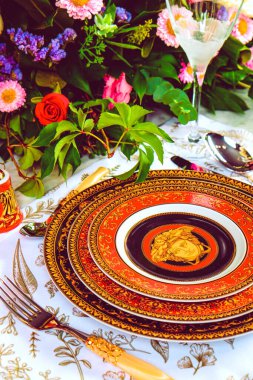 Güzel bir tabak ve mükemmel renkte çiçekler lüks bir masada duruyor.