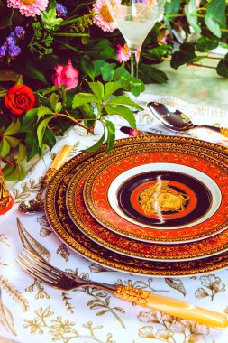 Güzel bir tabak ve mükemmel renkte çiçekler lüks bir masada duruyor.