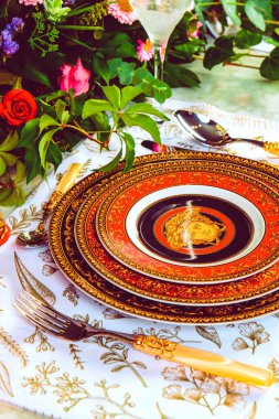 Güzel bir tabak ve mükemmel renkte çiçekler lüks bir masada duruyor.