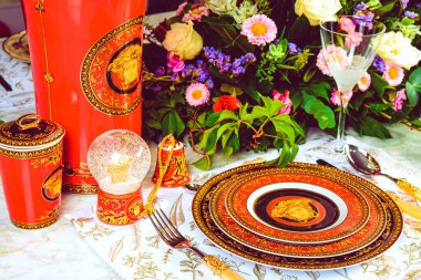 Güzel bir tabak ve mükemmel renkte çiçekler lüks bir masada duruyor.