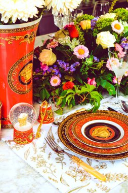 Güzel bir tabak ve mükemmel renkte çiçekler lüks bir masada duruyor.