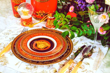 Güzel bir tabak ve mükemmel renkte çiçekler lüks bir masada duruyor.