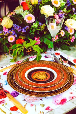 Güzel bir tabak ve mükemmel renkte çiçekler lüks bir masada duruyor.