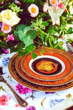 Güzel bir tabak ve mükemmel renkte çiçekler lüks bir masada duruyor.