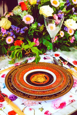 Güzel bir tabak ve mükemmel renkte çiçekler lüks bir masada duruyor.