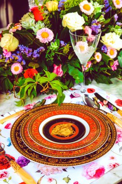 Güzel bir tabak ve mükemmel renkte çiçekler lüks bir masada duruyor.