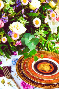 Güzel bir tabak ve mükemmel renkte çiçekler lüks bir masada duruyor.