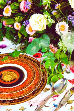 Güzel bir tabak ve mükemmel renkte çiçekler lüks bir masada duruyor.