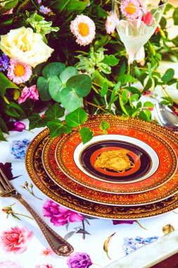 Güzel bir tabak ve mükemmel renkte çiçekler lüks bir masada duruyor.