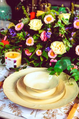 Güzel bir tabak ve mükemmel renkte çiçekler lüks bir masada duruyor.