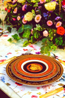 Güzel bir tabak ve mükemmel renkte çiçekler lüks bir masada duruyor.