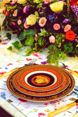 Güzel bir tabak ve mükemmel renkte çiçekler lüks bir masada duruyor.