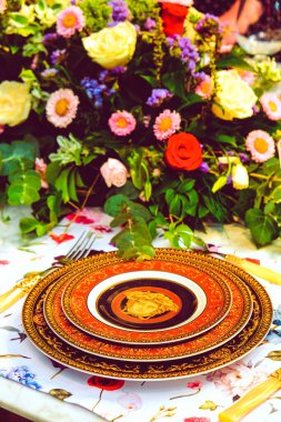 Güzel bir tabak ve mükemmel renkte çiçekler lüks bir masada duruyor.