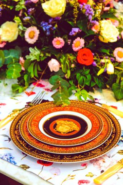 Güzel bir tabak ve mükemmel renkte çiçekler lüks bir masada duruyor.