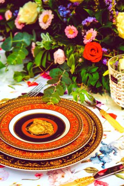 Güzel bir tabak ve mükemmel renkte çiçekler lüks bir masada duruyor.