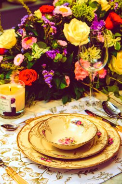 Güzel bir tabak ve mükemmel renkte çiçekler lüks bir masada duruyor.