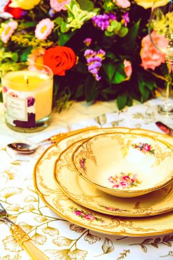 Güzel bir tabak ve mükemmel renkte çiçekler lüks bir masada duruyor.