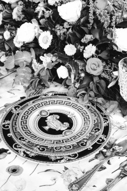 Güzel bir tabak ve mükemmel renkte çiçekler lüks bir masada duruyor.