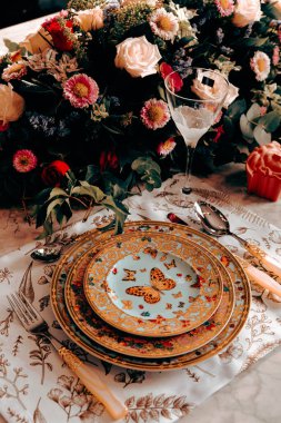 Güzel bir tabak ve mükemmel renkte çiçekler lüks bir masada duruyor.