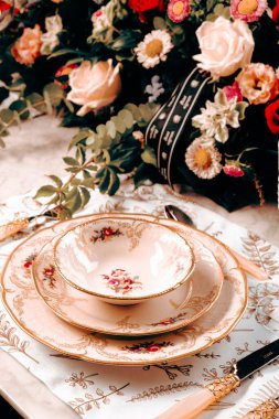 Güzel bir tabak ve mükemmel renkte çiçekler lüks bir masada duruyor.