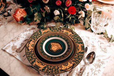 Güzel bir tabak ve mükemmel renkte çiçekler lüks bir masada duruyor.