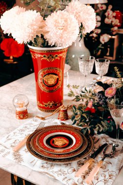 Güzel bir tabak ve mükemmel renkte çiçekler lüks bir masada duruyor.