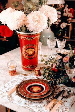 Güzel bir tabak ve mükemmel renkte çiçekler lüks bir masada duruyor.