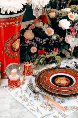 Güzel bir tabak ve mükemmel renkte çiçekler lüks bir masada duruyor.