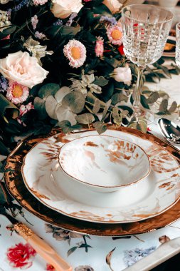 Güzel bir tabak ve mükemmel renkte çiçekler lüks bir masada duruyor.