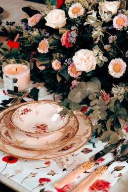 Güzel bir tabak ve mükemmel renkte çiçekler lüks bir masada duruyor.