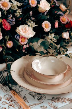 Güzel bir tabak ve mükemmel renkte çiçekler lüks bir masada duruyor.