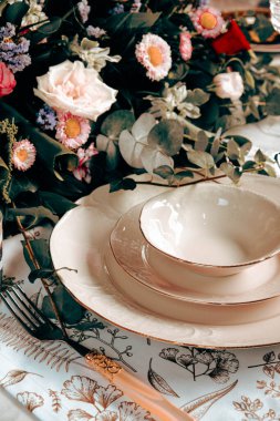 Güzel bir tabak ve mükemmel renkte çiçekler lüks bir masada duruyor.