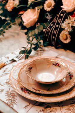 Güzel bir tabak ve mükemmel renkte çiçekler lüks bir masada duruyor.