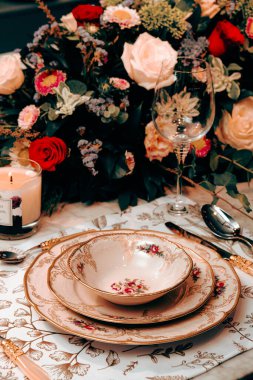 Güzel bir tabak ve mükemmel renkte çiçekler lüks bir masada duruyor.