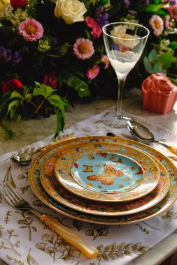 Güzel bir tabak ve mükemmel renkte çiçekler lüks bir masada duruyor.