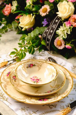 Güzel bir tabak ve mükemmel renkte çiçekler lüks bir masada duruyor.