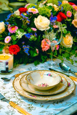 Güzel bir tabak ve mükemmel renkte çiçekler lüks bir masada duruyor.