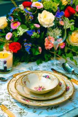 Güzel bir tabak ve mükemmel renkte çiçekler lüks bir masada duruyor.