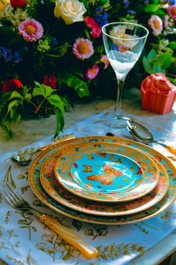 Güzel bir tabak ve mükemmel renkte çiçekler lüks bir masada duruyor.