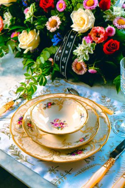 Güzel bir tabak ve mükemmel renkte çiçekler lüks bir masada duruyor.