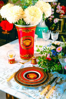 Güzel bir tabak ve mükemmel renkte çiçekler lüks bir masada duruyor.