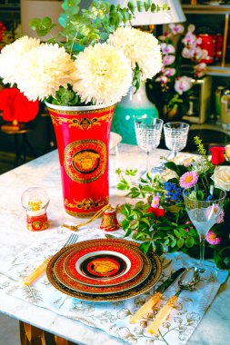 Güzel bir tabak ve mükemmel renkte çiçekler lüks bir masada duruyor.