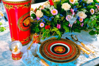 Güzel bir tabak ve mükemmel renkte çiçekler lüks bir masada duruyor.