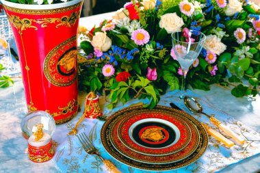 Güzel bir tabak ve mükemmel renkte çiçekler lüks bir masada duruyor.