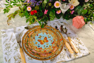 Güzel bir tabak ve mükemmel renkte çiçekler lüks bir masada duruyor.