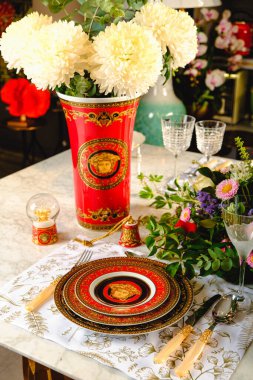 Güzel bir tabak ve mükemmel renkte çiçekler lüks bir masada duruyor.