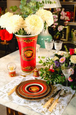 Güzel bir tabak ve mükemmel renkte çiçekler lüks bir masada duruyor.