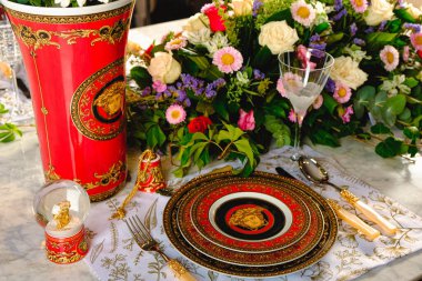 Güzel bir tabak ve mükemmel renkte çiçekler lüks bir masada duruyor.