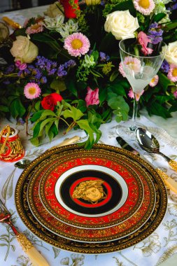 Güzel bir tabak ve mükemmel renkte çiçekler lüks bir masada duruyor.