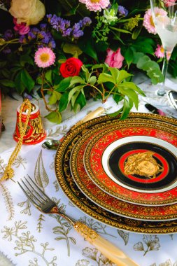 Güzel bir tabak ve mükemmel renkte çiçekler lüks bir masada duruyor.